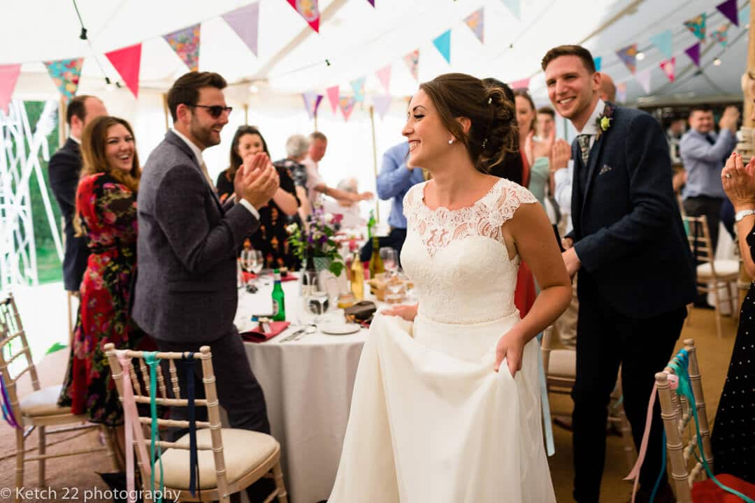 Wedding guests cheering bride and groom in Marquee