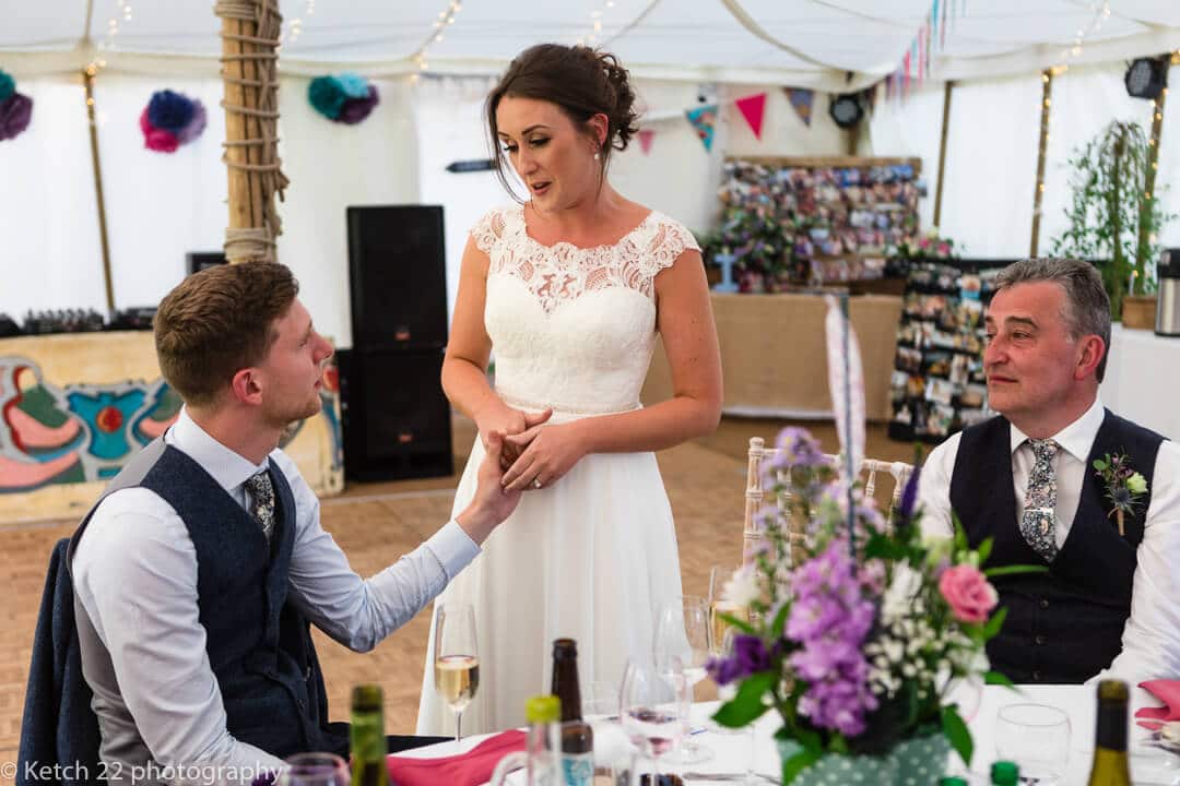 Bride holding grooms hand as she makes a speech