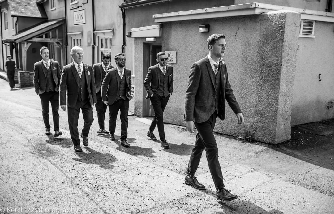 Groom and ushers walking in front of Lion Hotel in Herefordshire at Marquee wedding