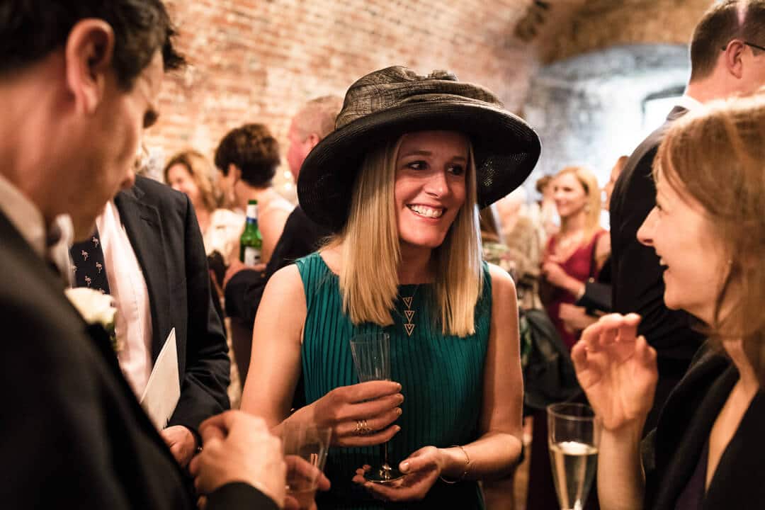Wedding guest wearing black hat and green dress at reception