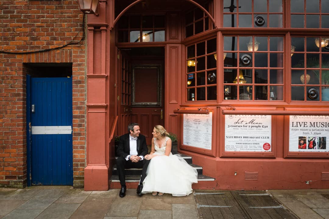 Bride and groom sat on pub steps at The Square Tower Wedding