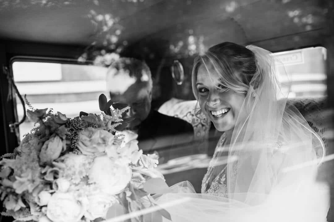 Bride smiling through wedding car window