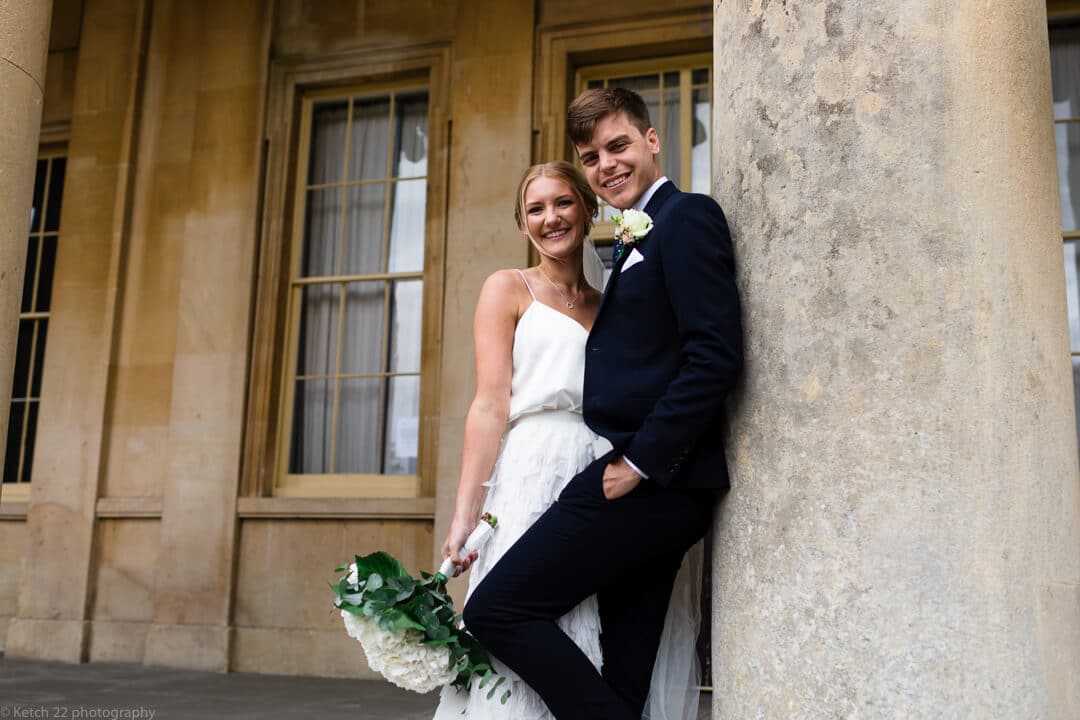 Bride and groom leaning on pillar at Cheltenham wedding