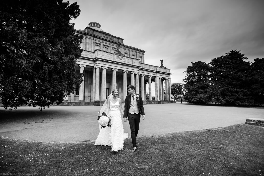 Bride and groom walking in front of Cheltenham pump rooms