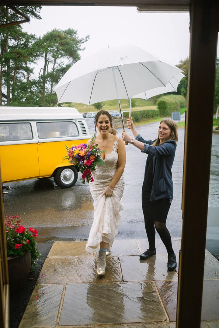 Bride arrives at Kingscote Barn wedding in the rain