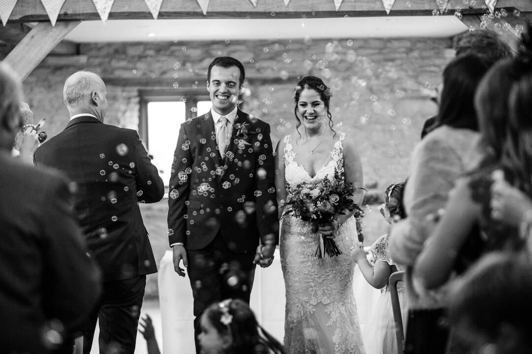 Bride and groom getting covered in bubbles at Kingscote Barn Wedding