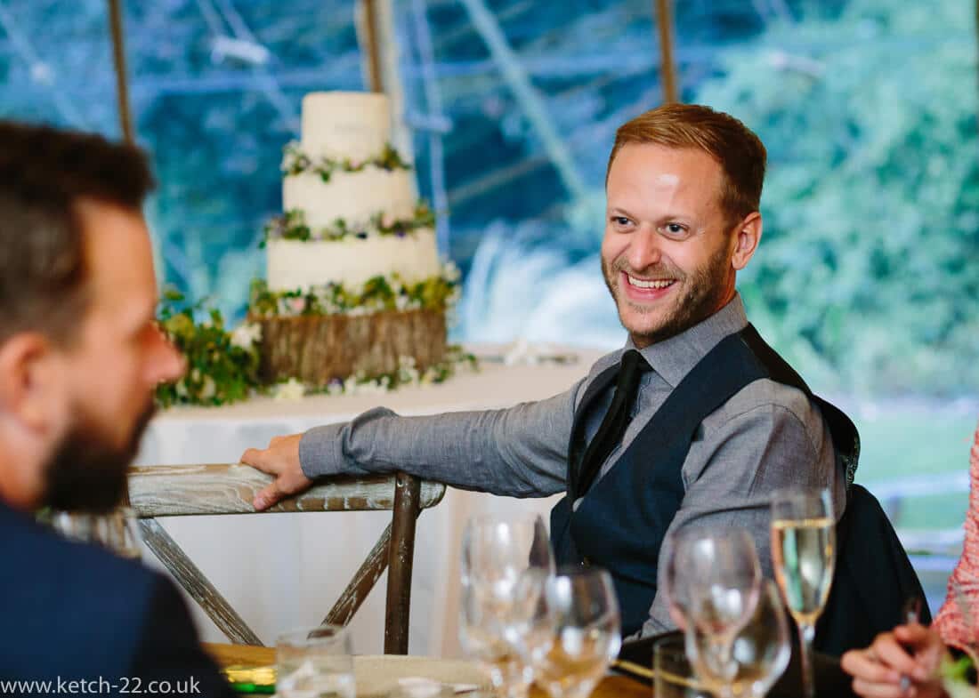 Man with waist coat listening to wedding speech