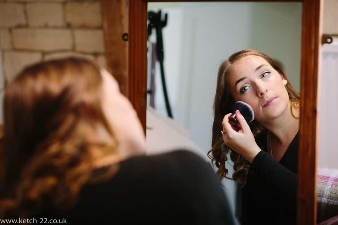 Bridesmaid powdering her face at wedding preparations