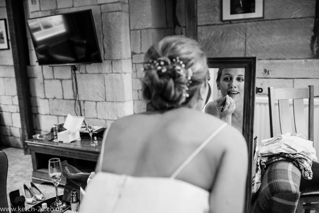 Bride putting on lip stick in mirror - Winchcombe wedding photographer