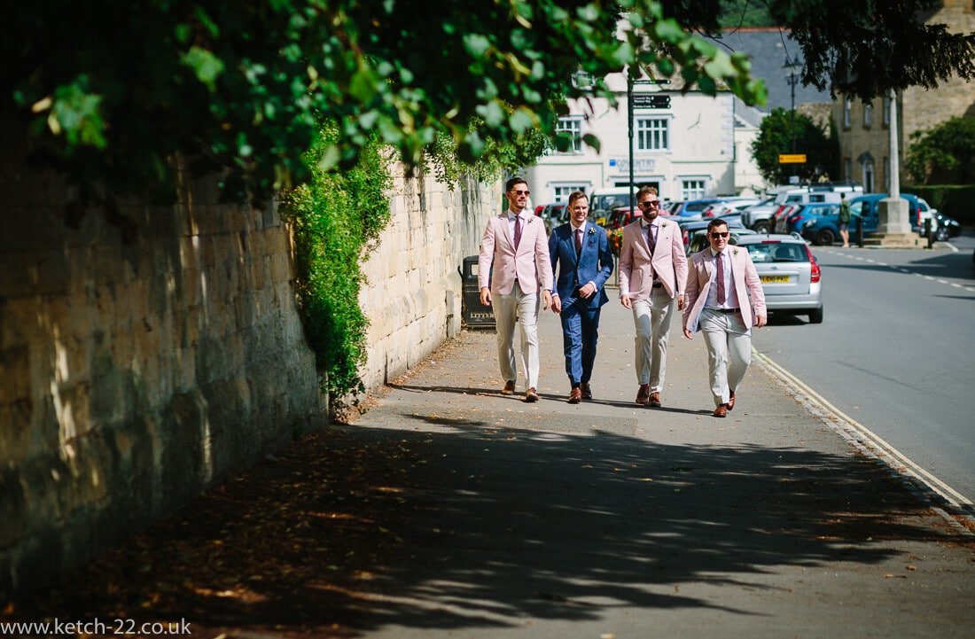 Groom and groomsmen walking down street at Winchcombe wedding in Gloucestershire