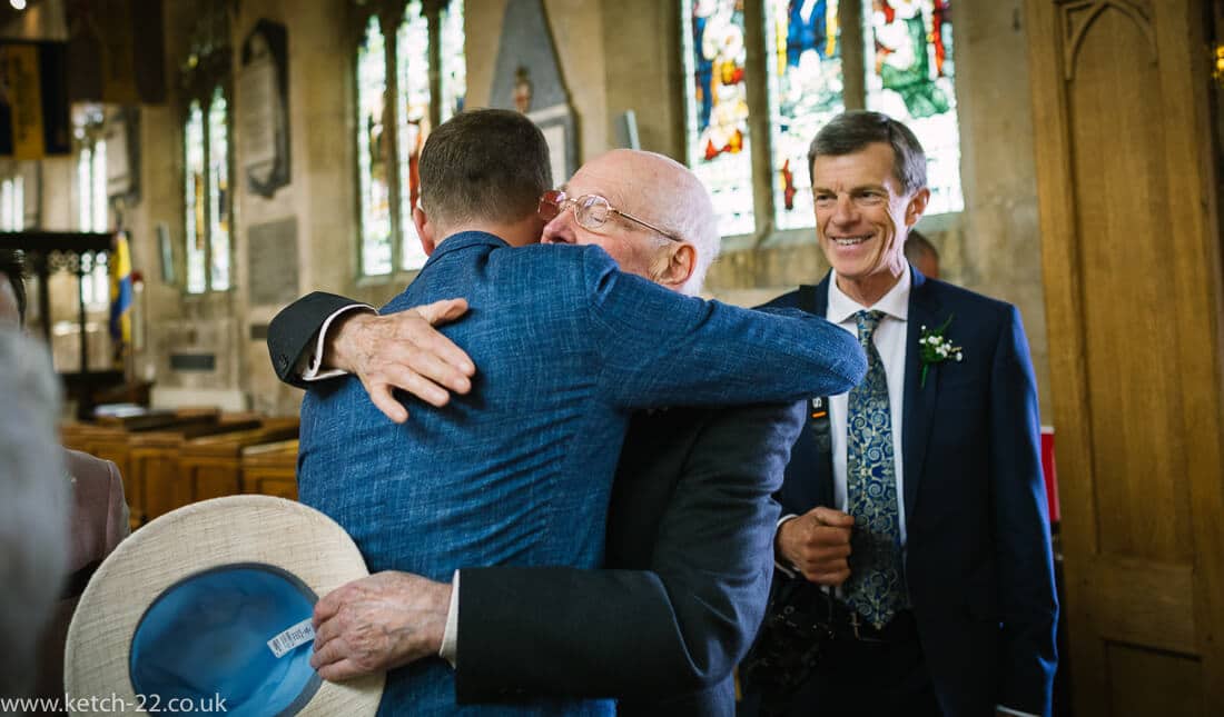 Groom hugging grand dad at church wedding