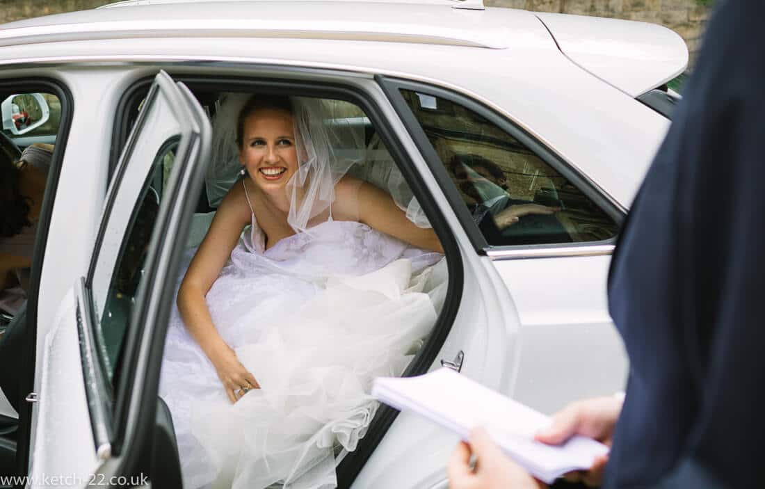 Bride getting out of white wedding car