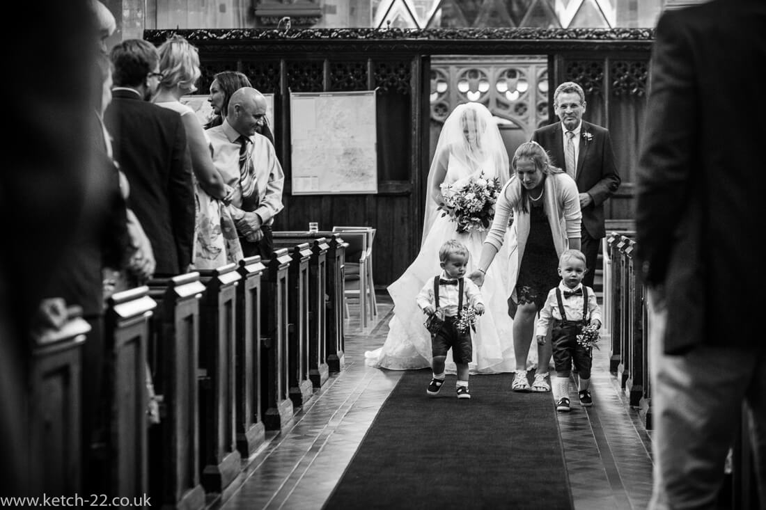 Bride, father and page boys walking down church ailse at wedding