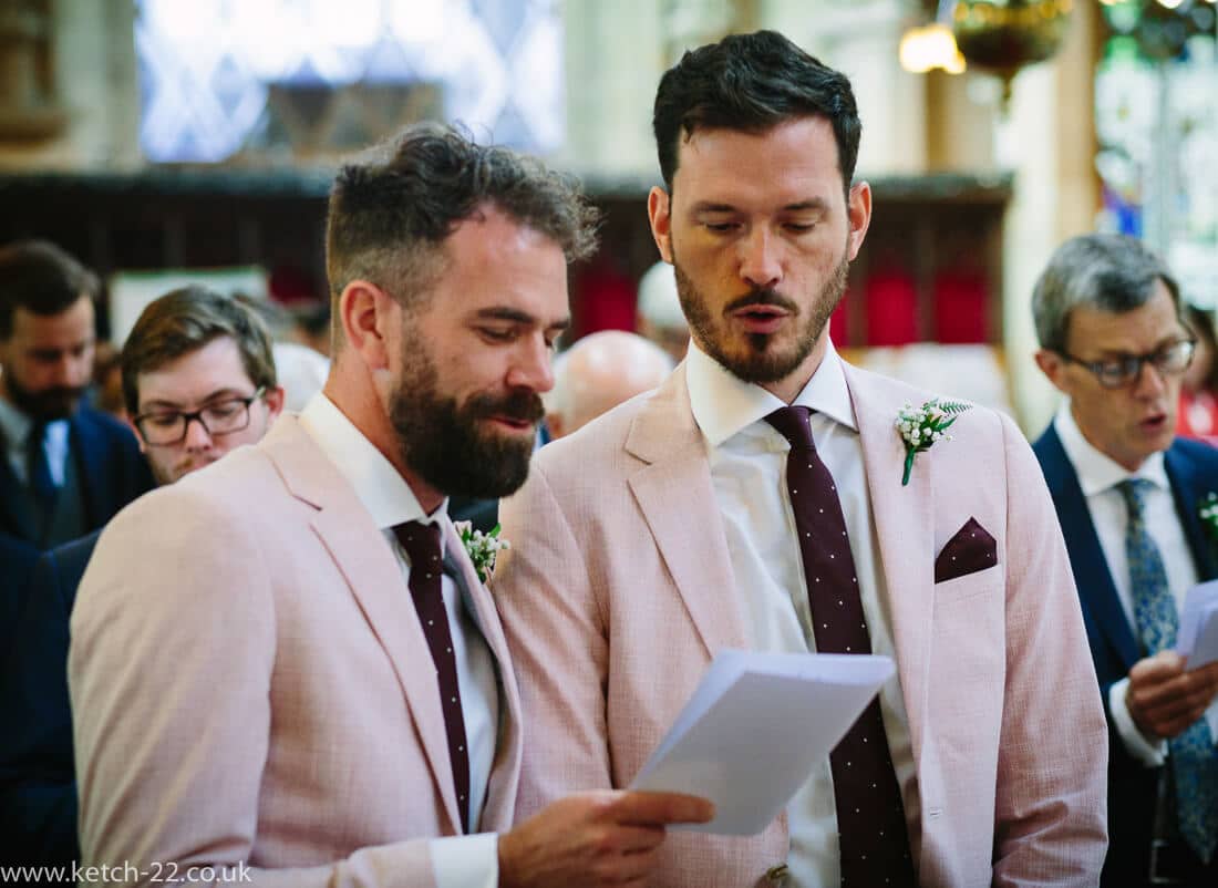 Groomsmen singing from song sheet 