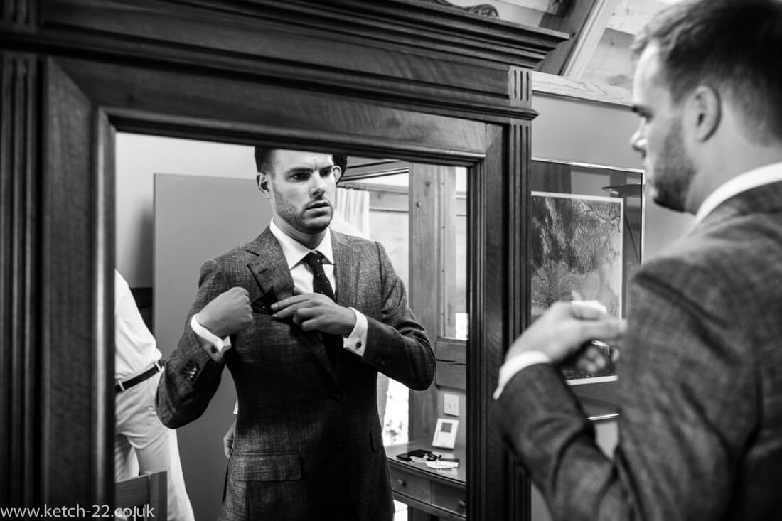 Groom looking into mirror at Winchcombe wedding preparations