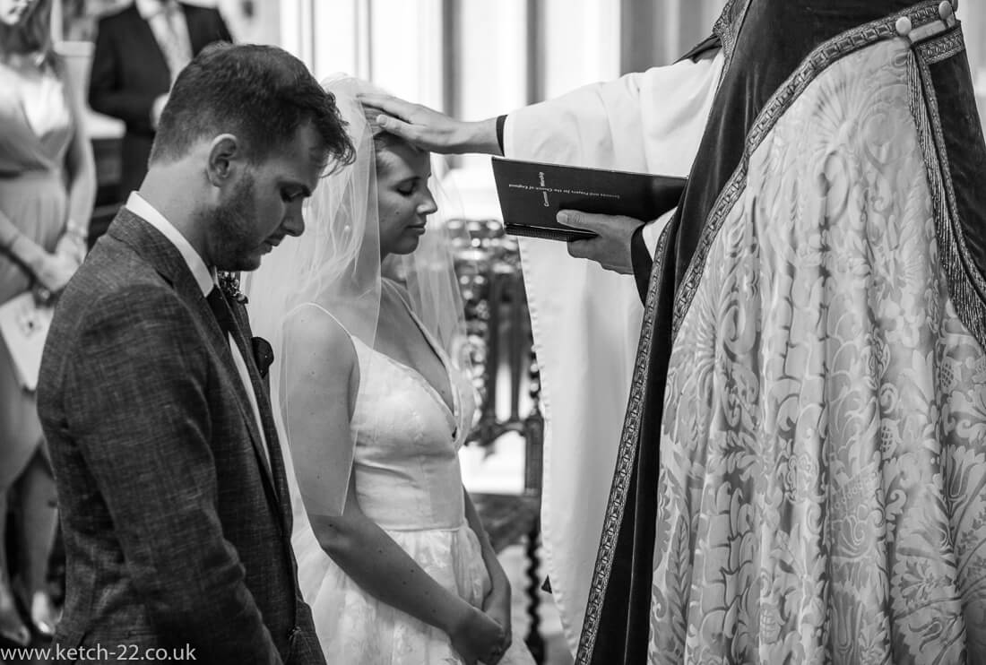 Vicar blessing bride and groom at Gloucestershire wedding