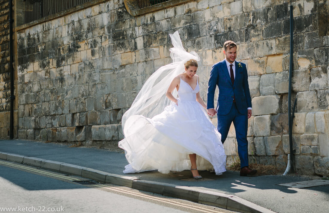 Bride and groom walking down street at summer wedding