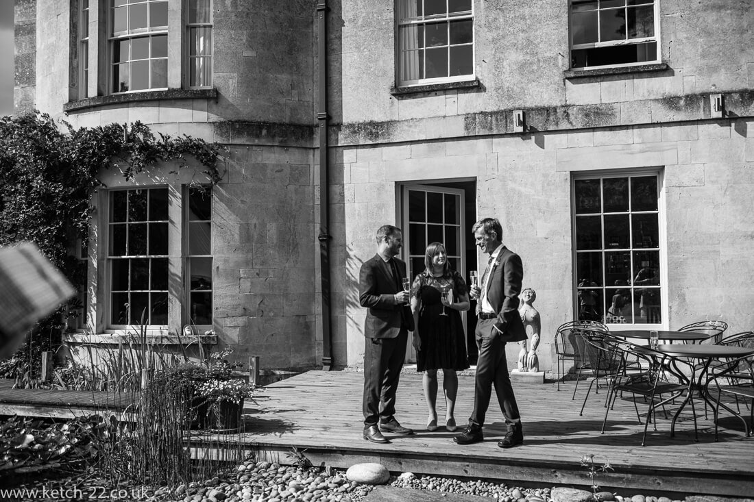 Wedding guests enjoy drinks outside country house