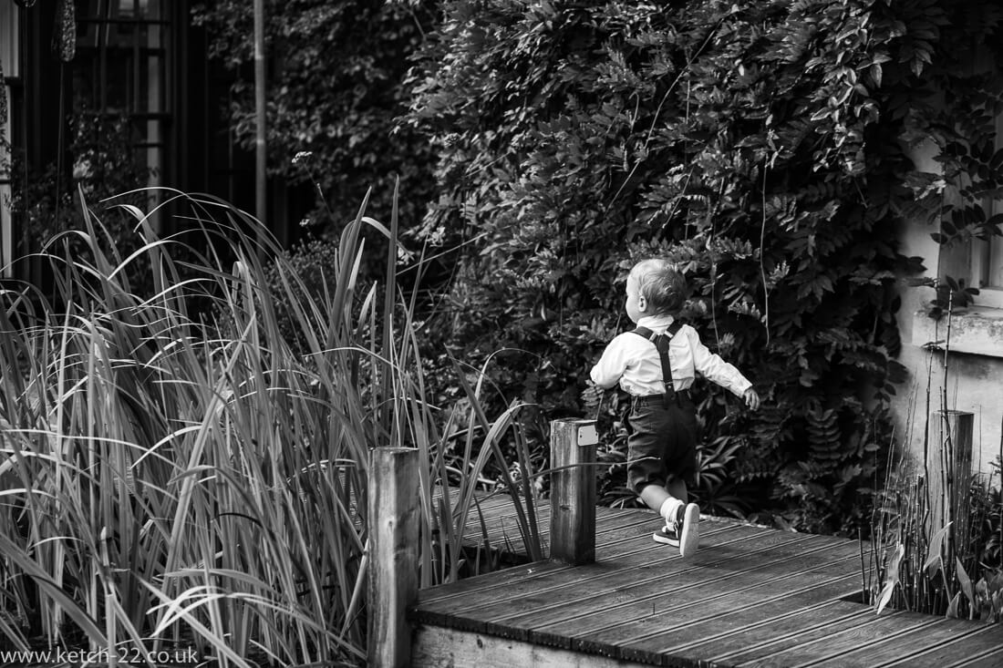 Page boy running in garden at Gloucestershire wedding