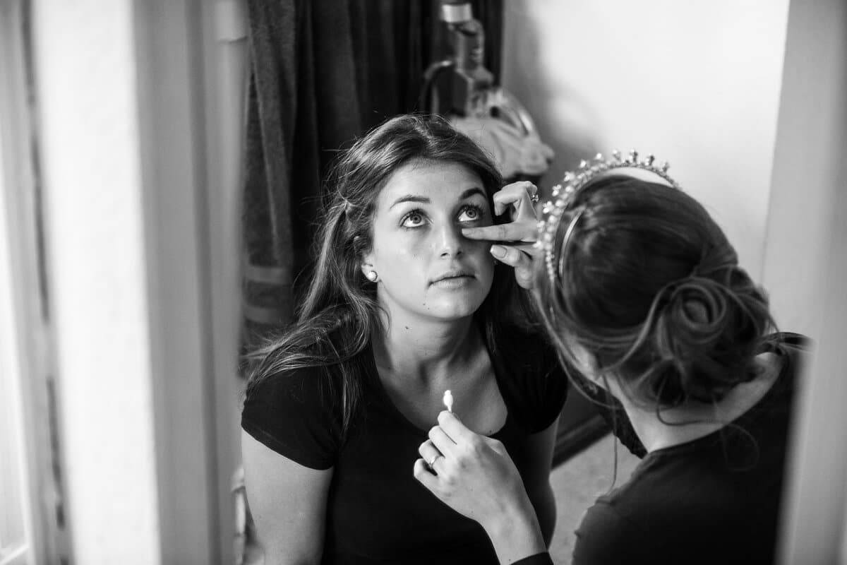 Bride putting makeup on bridesmaid before wedding