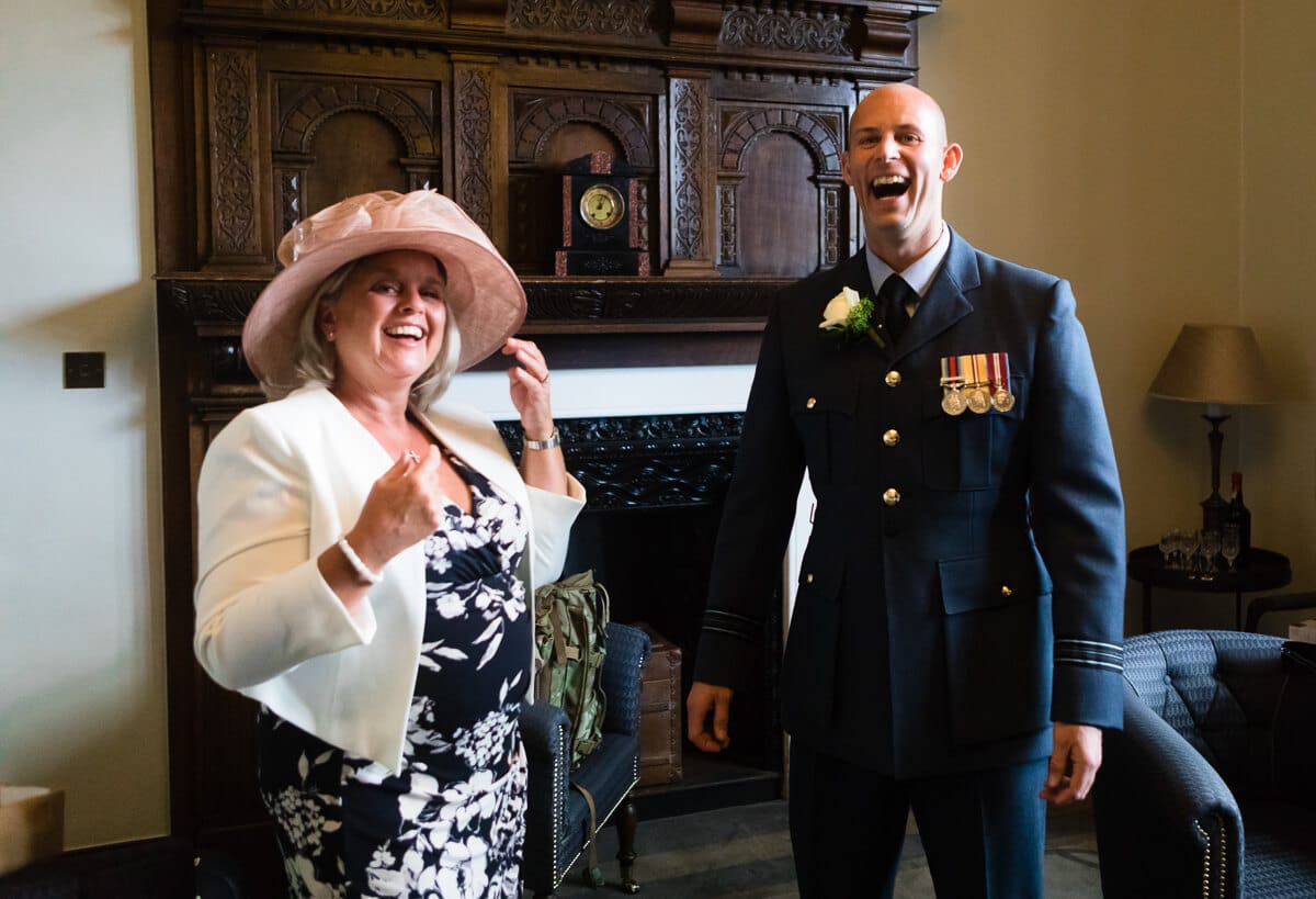 Groom in RAF uniform laughing with wedding guest