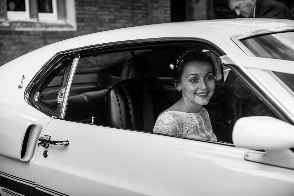 Bride looking out of GT 500 classic car at wedding