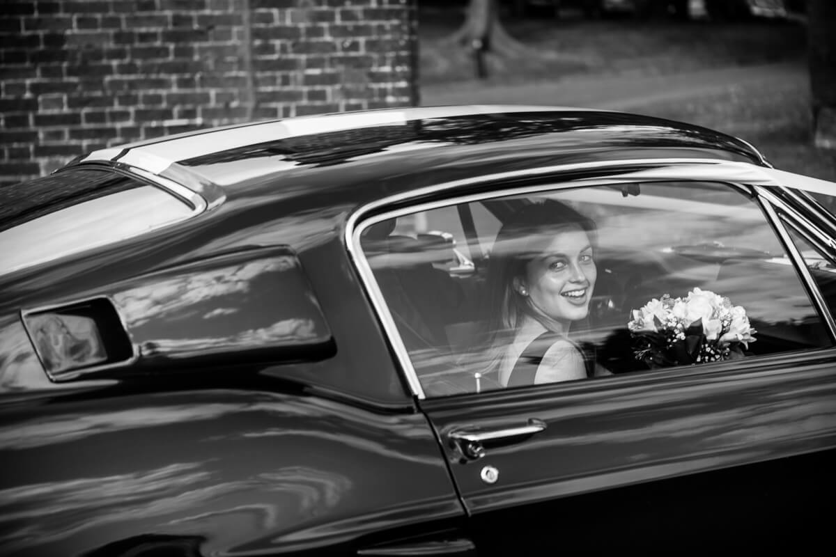 Brides sister looking out of GT 500 classic car at De Vere Latimer Estate Wedding