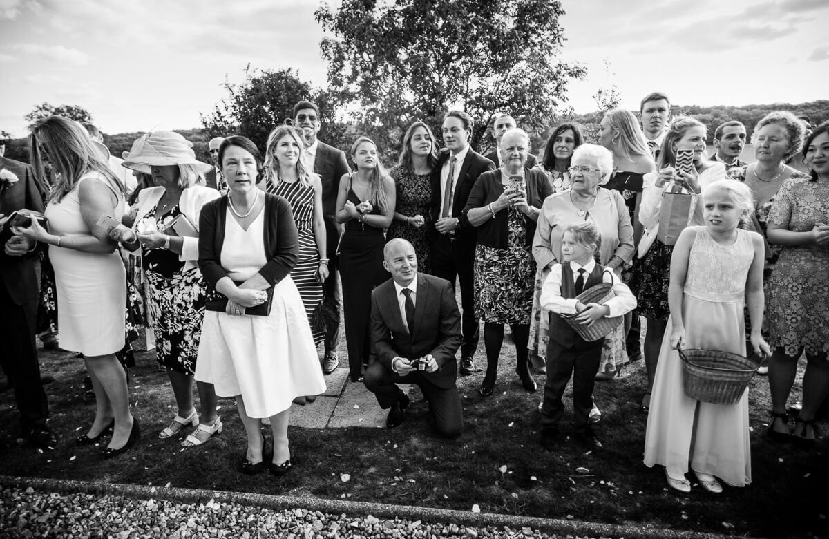 Wedding guests looking up as bride walks down steps