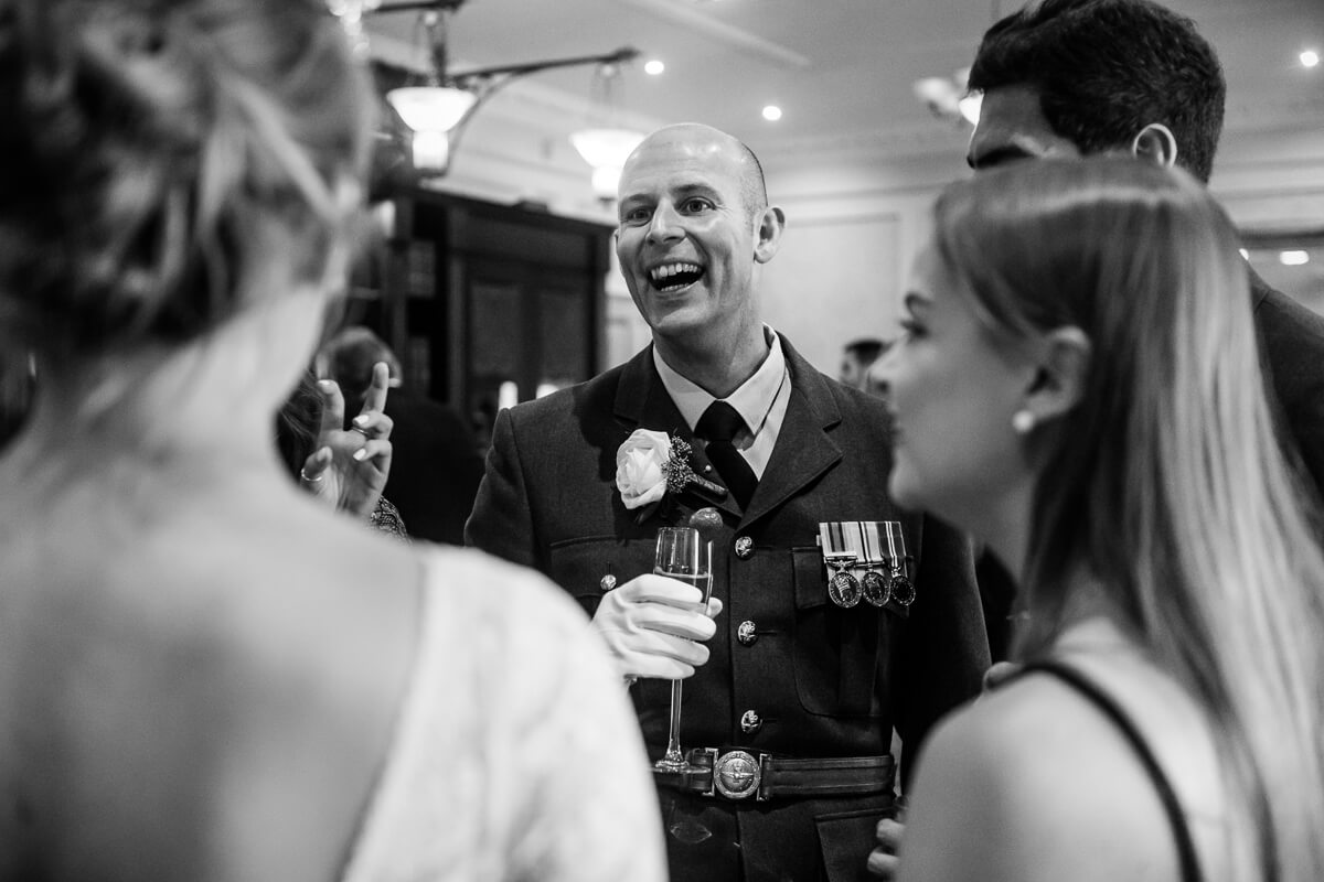 Groom in RAF uniform laughing and chatting with wedding guests