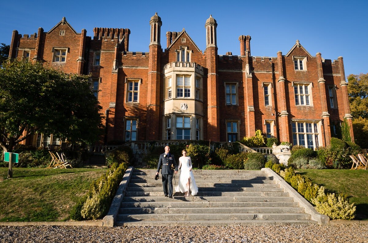 Bride and groom walking down grand steps at De Vere Latimer Estate wedding