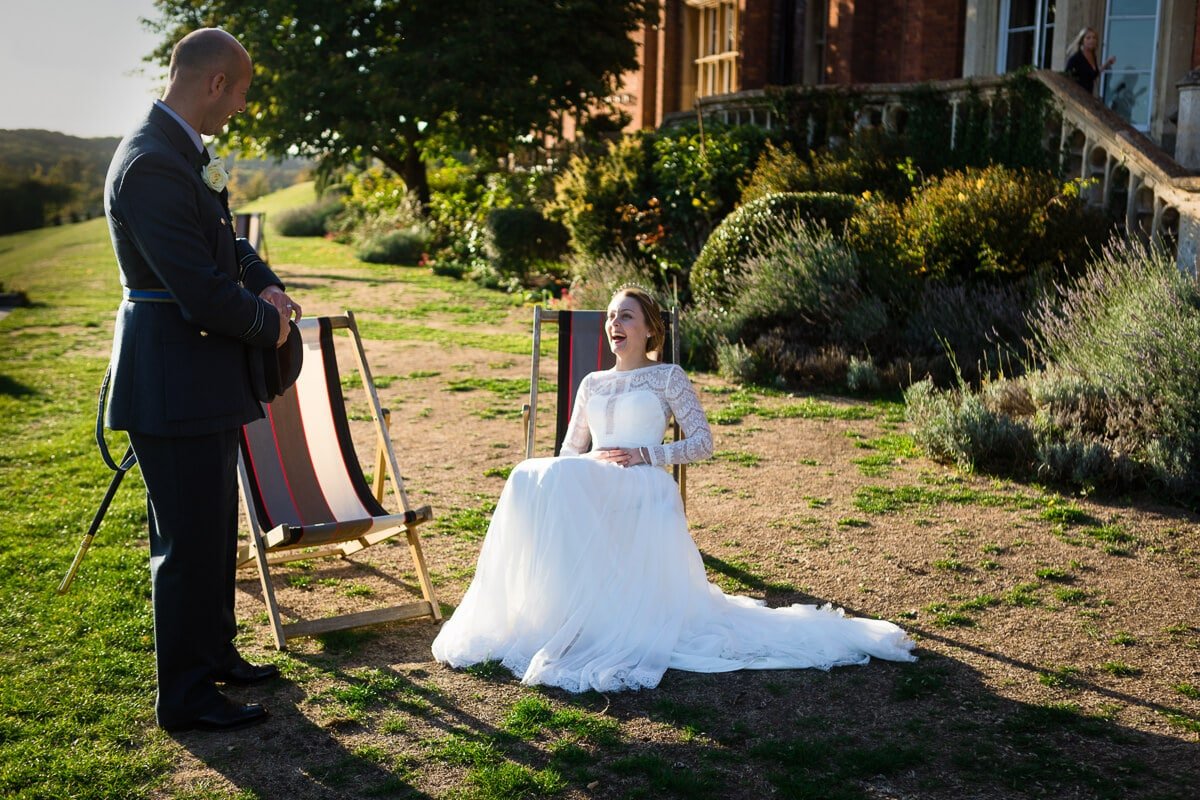 Bride sat in deck chair laughing at groom at de Vere Latimer Estate wedding