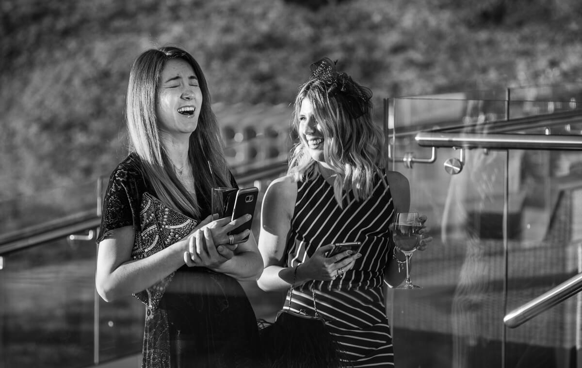 Two lady wedding guests laughing at garden reception