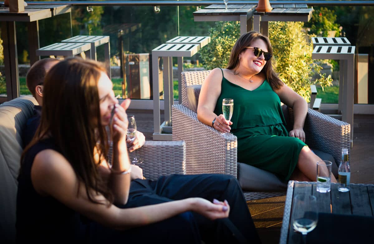 Wedding guest in green dress relaxing and drinking champagne