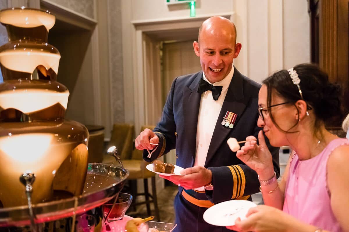 Groom chatting to wedding guest at chocolate fountain