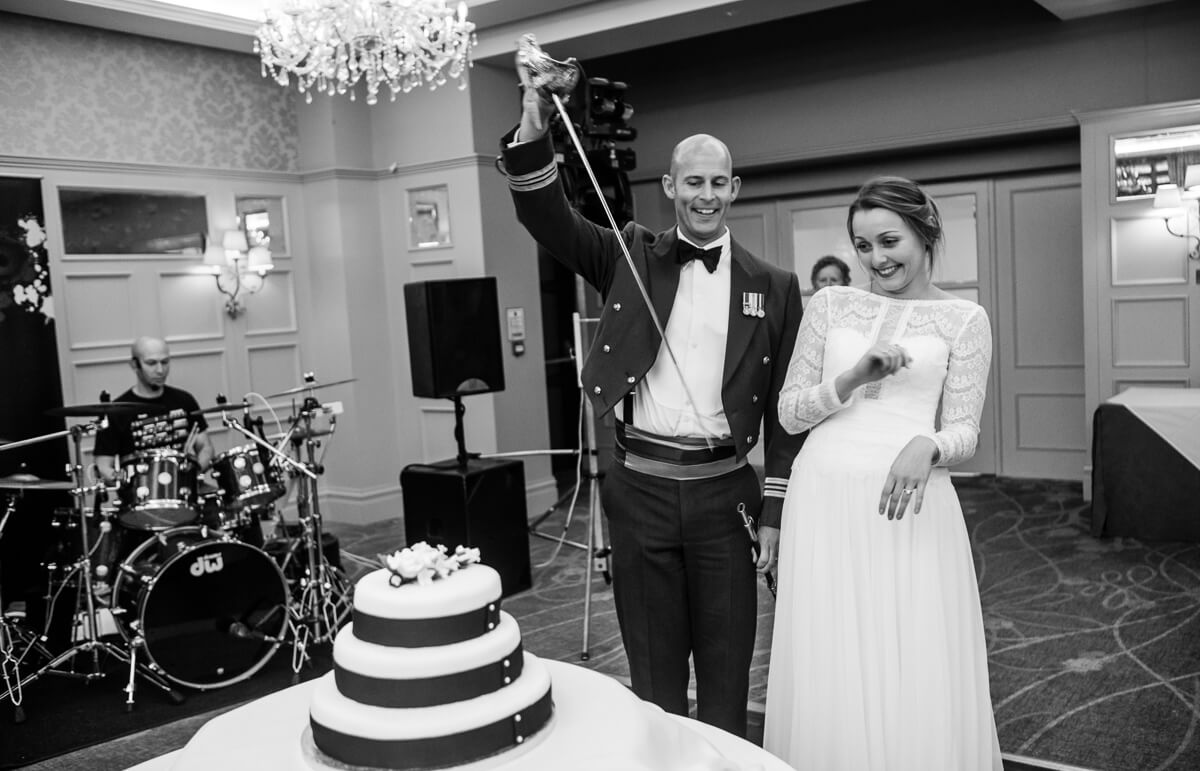 RAF groom and bride playing with sword before cutting the Wedding cake