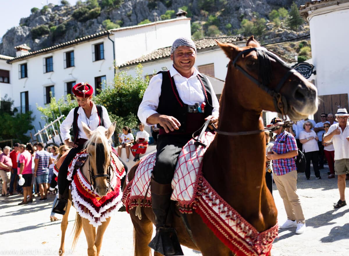 Man and woman riding horses wearing colourful costumes at Andalusian fiesta 