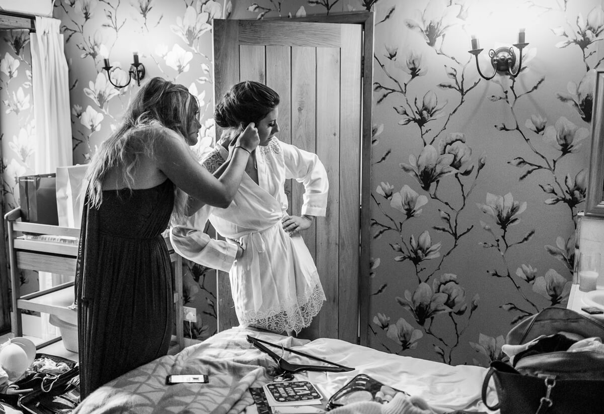 Bride having her ear rings put on by bridesmaid