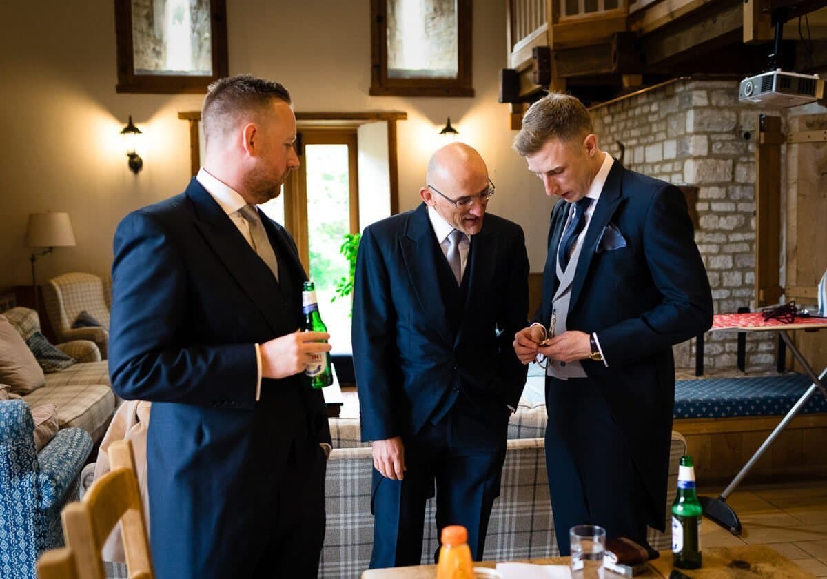 Groom showing off pocket watch at Cotswold Wedding, Cripps Barn