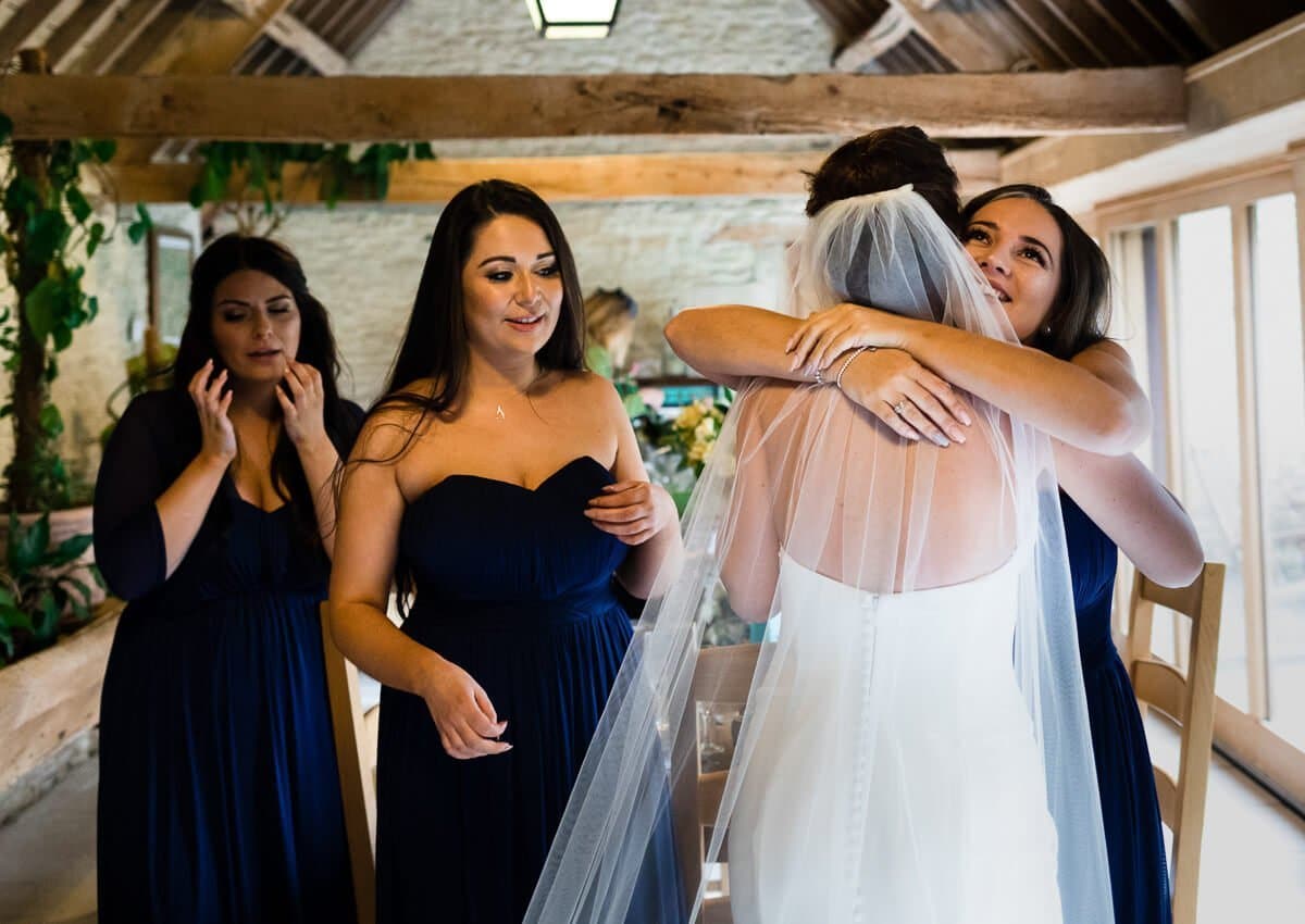 Bridesmaid hugging bride at Barn Wedding