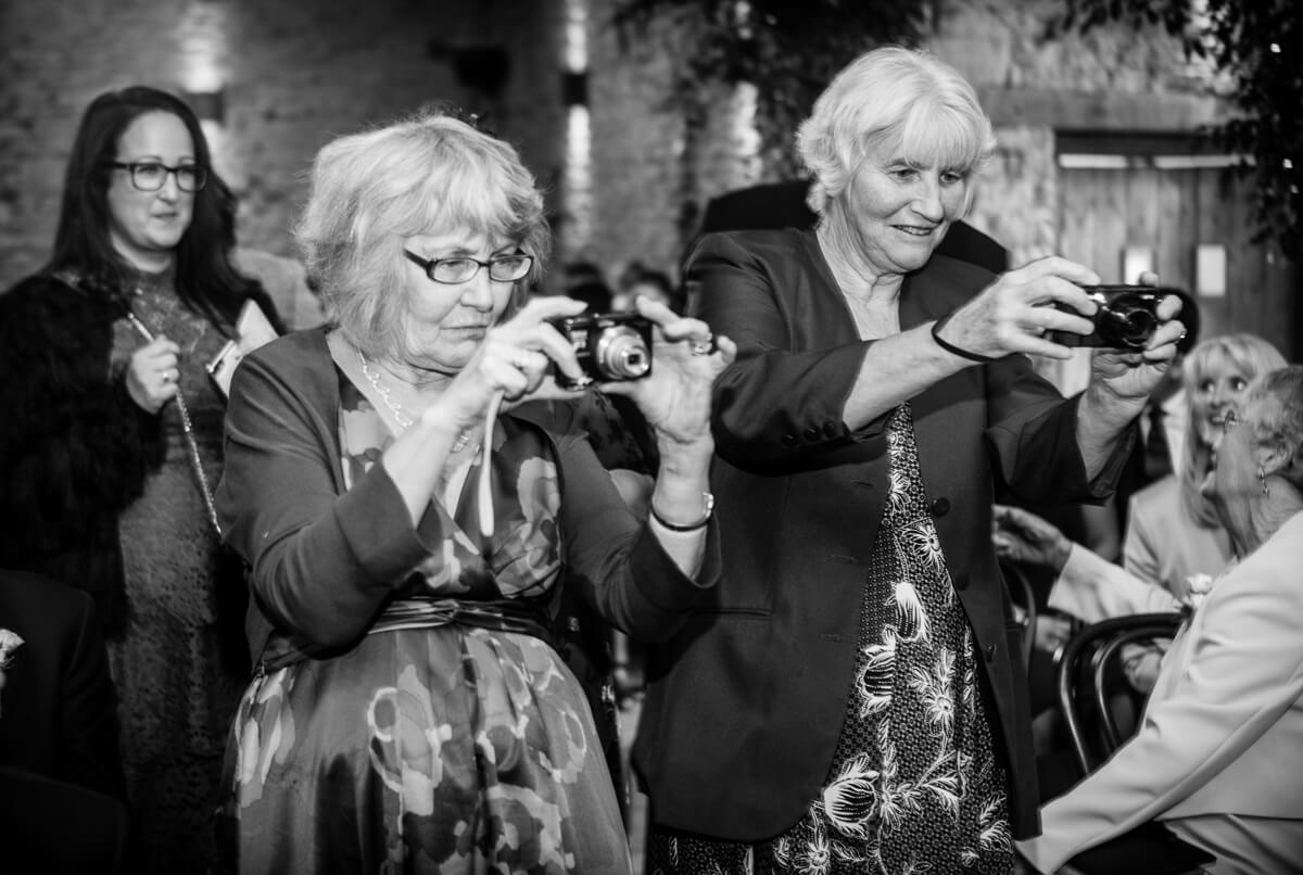 Wedding guests taking photos of newly wed couple